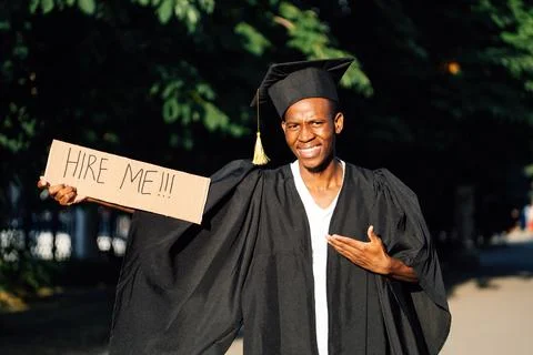 Portrait of smiling black guy standing and pointing at cardboard poster on Stock Photos