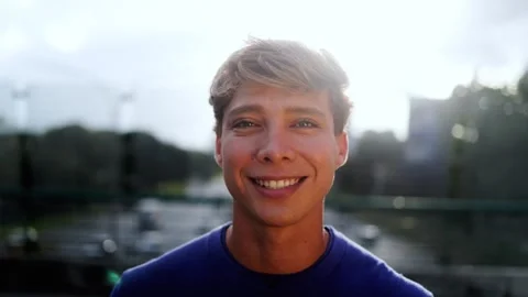 Portrait of smiling blond man looking at camera with city bridge in background   Stock Footage 313496191