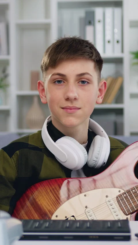 Portrait smiling boy looking at camera. European male learning an electro guitar Stock Footage 325993627