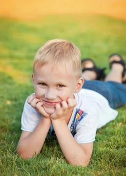 Portrait of a smiling boy lying on green grass. Stock Photos