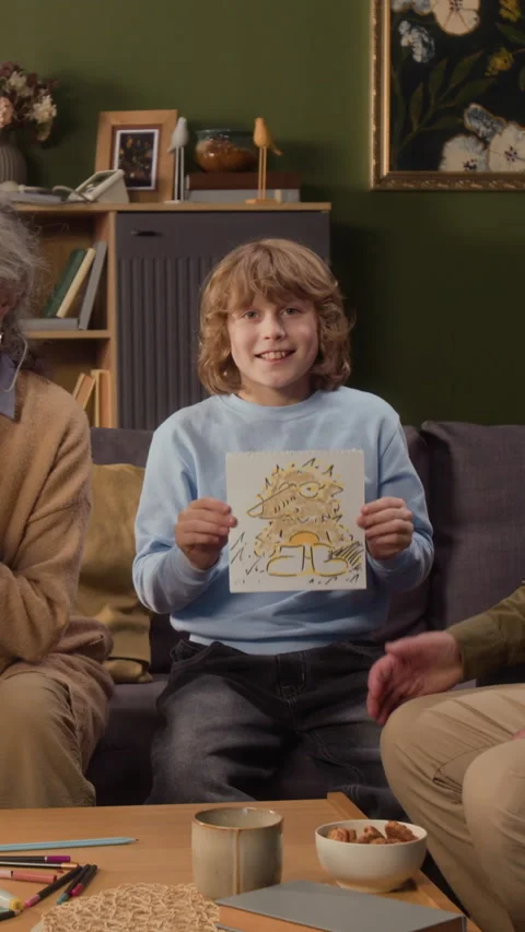 Portrait of Smiling Boy Showing Drawing to Camera with Grandparents Stock Footage 336940731