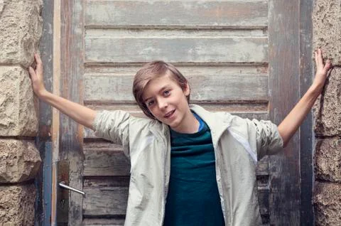 Portrait of a smiling boy standing in front of an old entrance Stock Photos