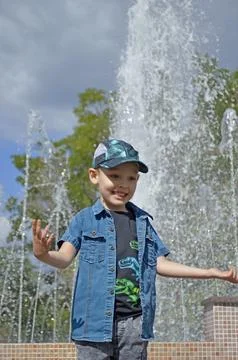 Portrait of a smiling boy while walking near a fountain Stock Photos