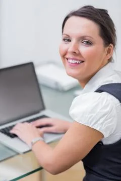 Portrait of smiling business woman using laptop at desk Stock Photos