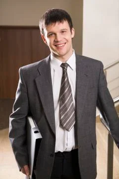 Portrait of smiling businessman in the suit with black case in his hands Stock Photos