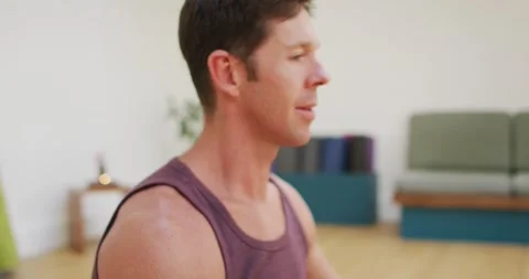 Portrait of smiling caucasian man practicing yoga sitting in lotus position at Stock Footage 337931845