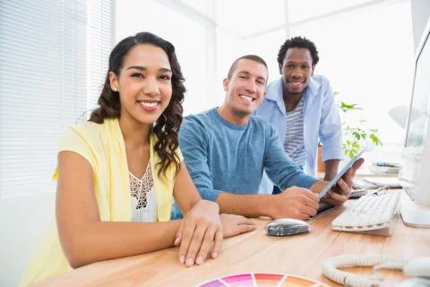 Portrait of smiling colleagues using tablet computer and looking at camera Stock Photos