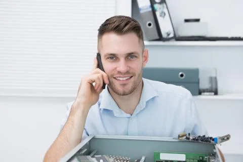 Portrait of smiling computer engineer on call in front of open cpu Foto stock