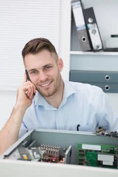 Portrait of smiling computer engineer on call in front of open cpu Foto stock