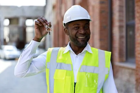 Portrait of smiling construction engineer holding keys from new home. African Stock Photos