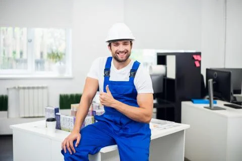 A portrait of a smiling construction worker in a hard hat showing thumbs up Stock Photos