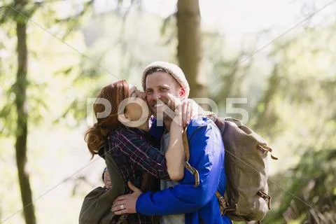 Portrait smiling couple kissing hiking in woods Stock Photos