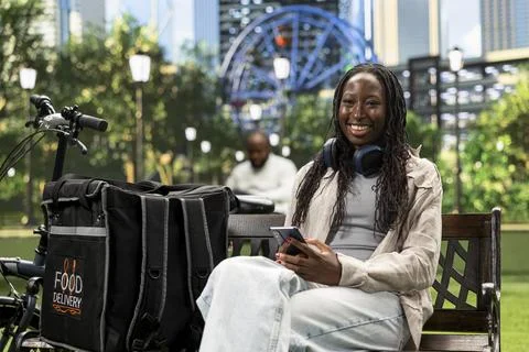 Portrait of smiling courier looking at the camera seated with smartphone Stock Photos