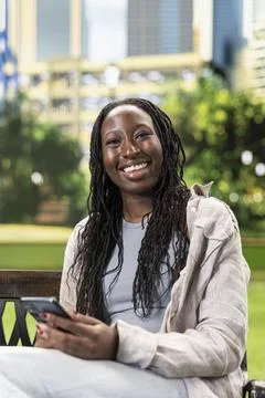 Portrait of smiling courier looking at the camera seated with smartphone Stock Photos
