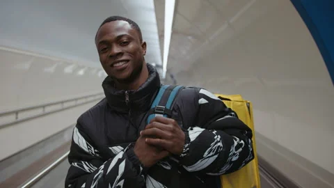 Portrait of smiling courier with a yellow backpack who delivers to the customer Stock Footage 279726802
