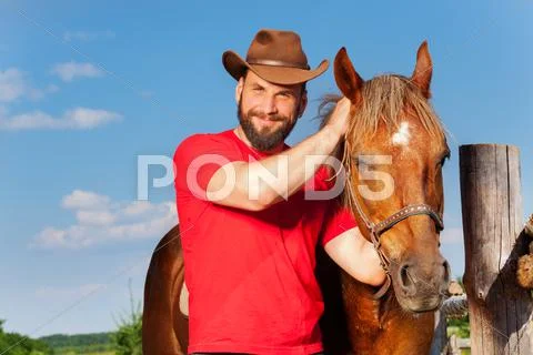 Portrait of smiling cowboy with his bay horse Stock Photos