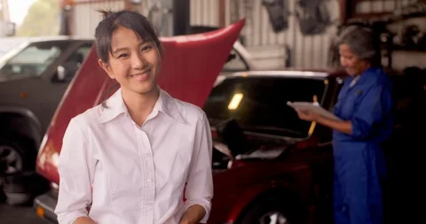 Portrait of smiling customer while a mechanic works on a car in the background. Video stock 93441582