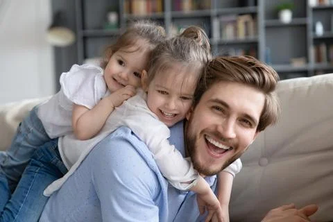 Portrait of smiling dad play with small daughters Stock Photos