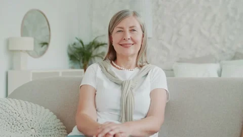 Portrait smiling elder middle age woman using smartphone sitting on sofa at home Vídeos de archivo 224532371