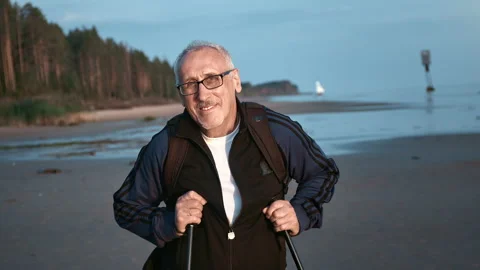 Portrait smiling elderly male backpacker posing with walking stick at sunset Stock-Footage 220022366