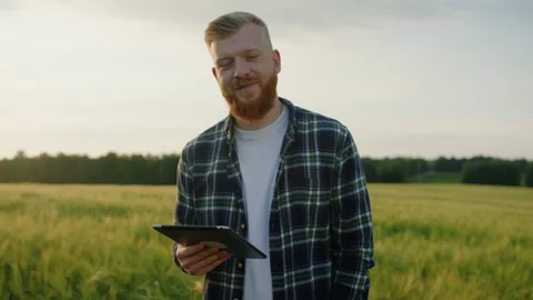 Portrait of a smiling farmer with a tablet in his hands, background of fields Stock Footage 234589023