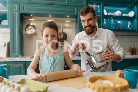 Portrait of smiling father and daughter baking in the kitchen Stock Photos
