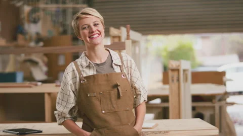 Portrait Of Smiling Female Apprentice Working As Carpenter In Furniture Workshop 스톡 동영상 242359517