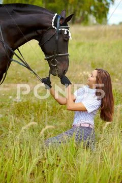 Portrait of smiling female feeding purebred horse with grass outdoors Stock Photos