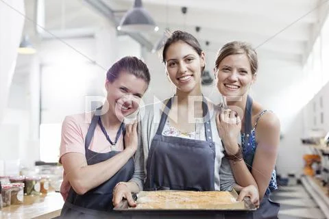 Portrait smiling female friends enjoying cooking class in kitchen Stock Photos