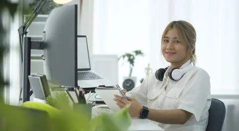 Portrait of smiling female IT developer sitting front of large curved compu.. Stock Photos