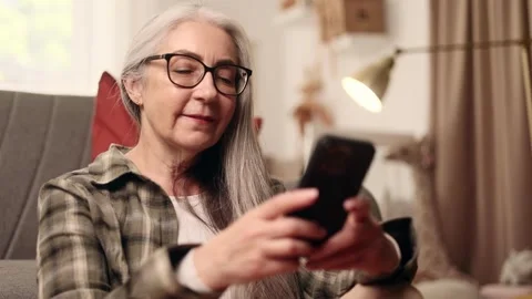 Portrait of smiling gray haired senior woman hold smartphone scrolling social Stock Footage 252127122