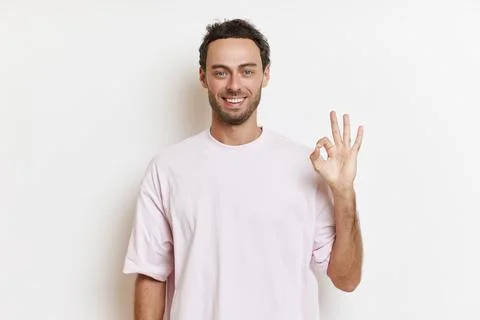 Portrait of smiling guy with beard posing against white background, showing OK Stock-Fotos