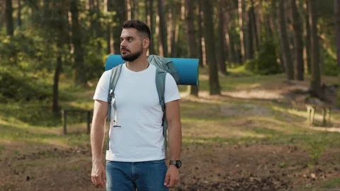 Portrait smiling handsome young man hiker standing in the forest look at camera Stock Footage 115501447