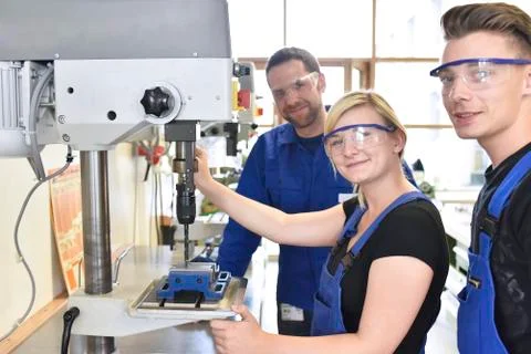 Portrait of smiling instructor with trainees at drill machine Stock Photos