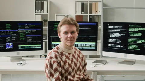 Portrait of Smiling Male IT Developer Sitting against Computer Screens in Office Video stock 330125271