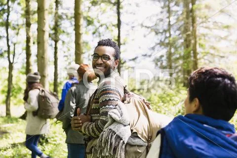 Portrait smiling man with backpack hiking in sunny woods Stock Photos