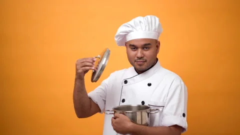 Portrait of smiling man chef standing and open pot on isolated yellow background Stock Footage 172284135