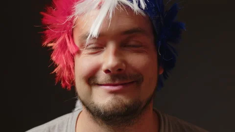 Portrait of a smiling man in a colored wig close-up on a gray background. The Stock Footage 228987275