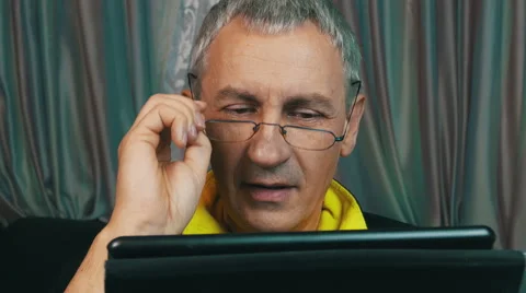 Portrait Smiling Man in Glasses Reading a Tablet Computer Video stock 47785155