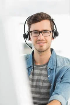 Portrait of a smiling man with headset using computer Stock Photos
