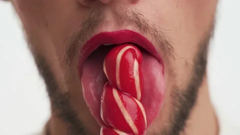 Portrait smiling man with makeup lick sweet sugar lollipop on white background Stock Footage 147574204