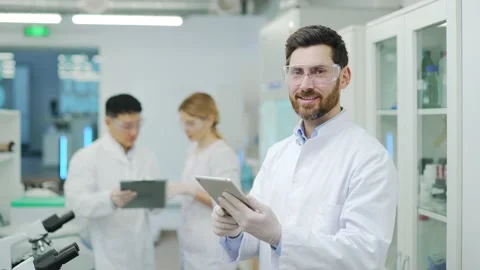 Portrait of smiling man scientist with protective glasses and gloves working  Stock Footage 233308880