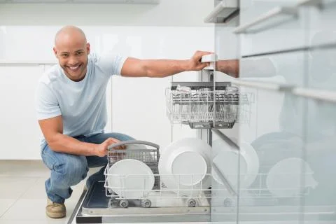 Portrait of smiling man using dish washer in kitchen Stock Photos