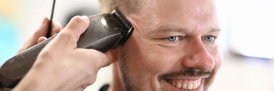 Portrait of smiling man whose master cuts with machine. Stock Photos