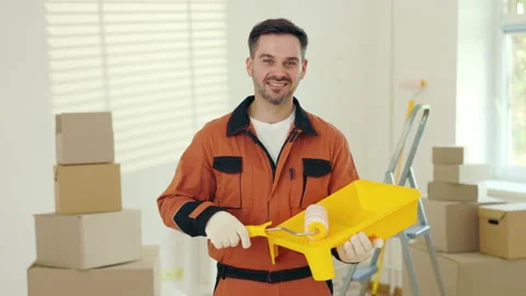 Portrait of the smiling man worker standing, holding paint roller and plastic Stock Footage 227699890