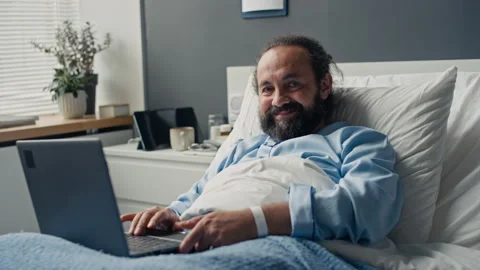 Portrait of Smiling Middle Aged Man Using Laptop in Hospital Bed Stock Footage 347886324