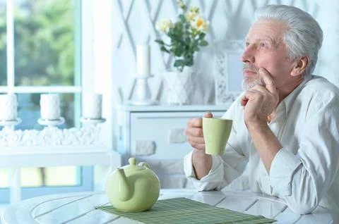 Portrait of smiling old man drinking tea at home Stock Photos