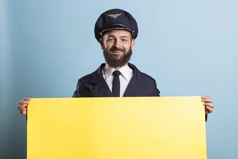 Portrait of smiling pilot standing behind large blank yellow board 写真素材