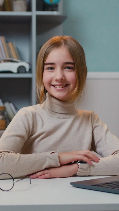 Portrait of smiling pretty 10-11 years old girl sitting at table in home. Positi Stock Footage 330190982