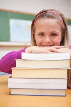 Portrait of a smiling schoolgirl posing with a stack of books Stockfoto's